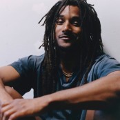 Jordan Ward sat on the ground wearing a blue tshirt and gold chain